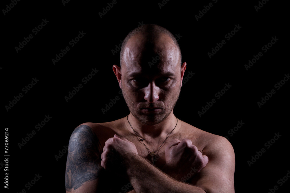 Silhouette of serious man with crossed hands and tattoo Silhouette of serious man with crossed hands and tattoo