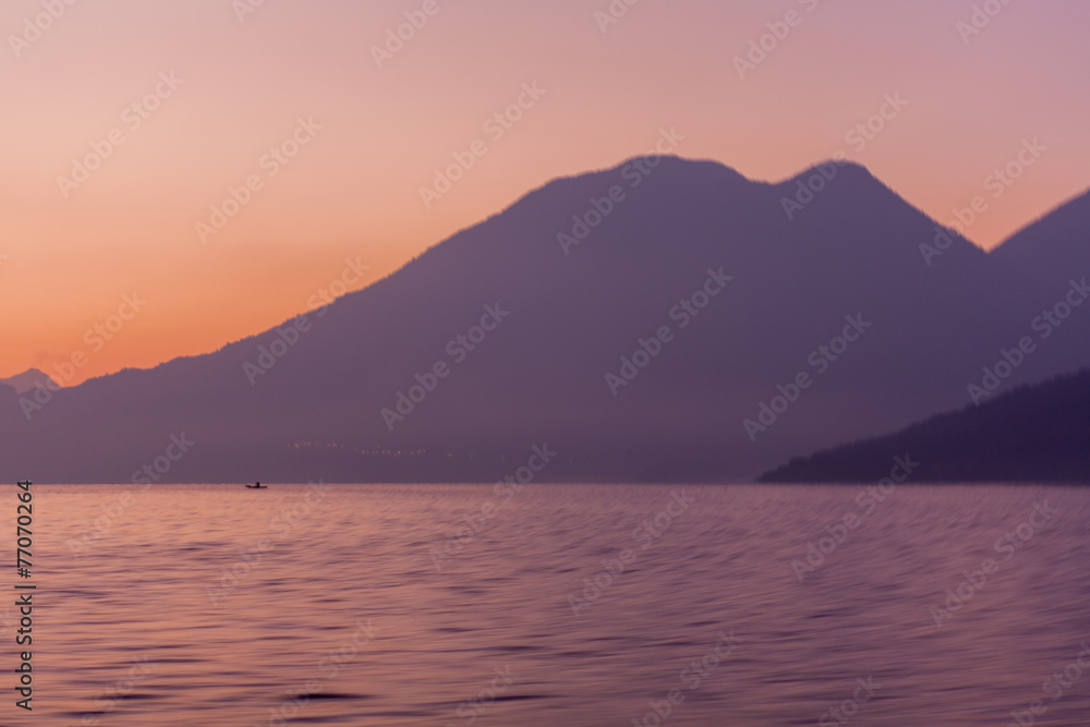 Lake Atitlan and volcanoes and boat in the morning