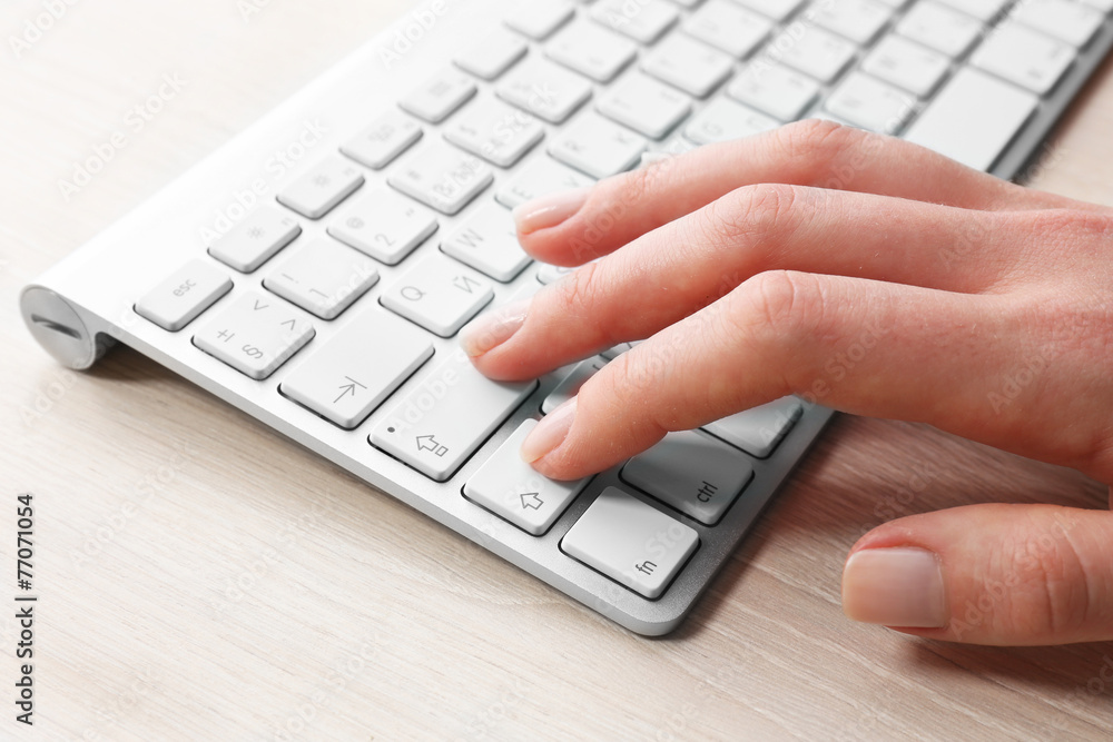 Female hand with keyboard on wooden desktop background Female hand with keyboard on wooden desktop background
