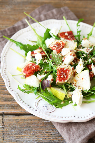 Delicious salad with arugula, slices of cheese and pears on a pl