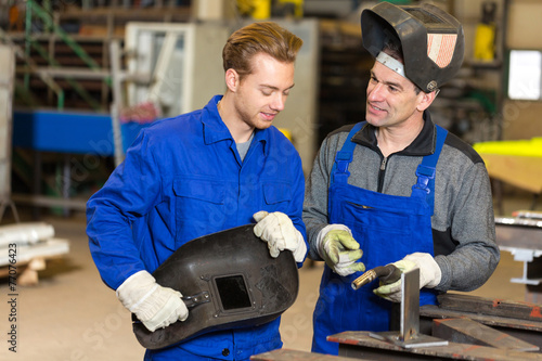 Instructor teaching trainee how to weld metal
