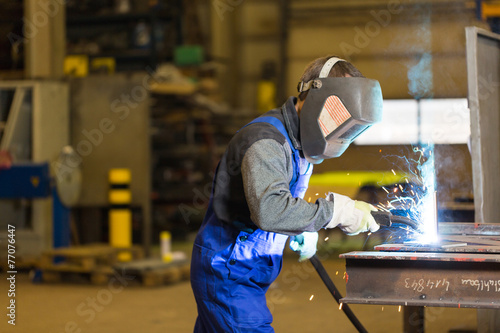 Steel construction worker welds metal parts