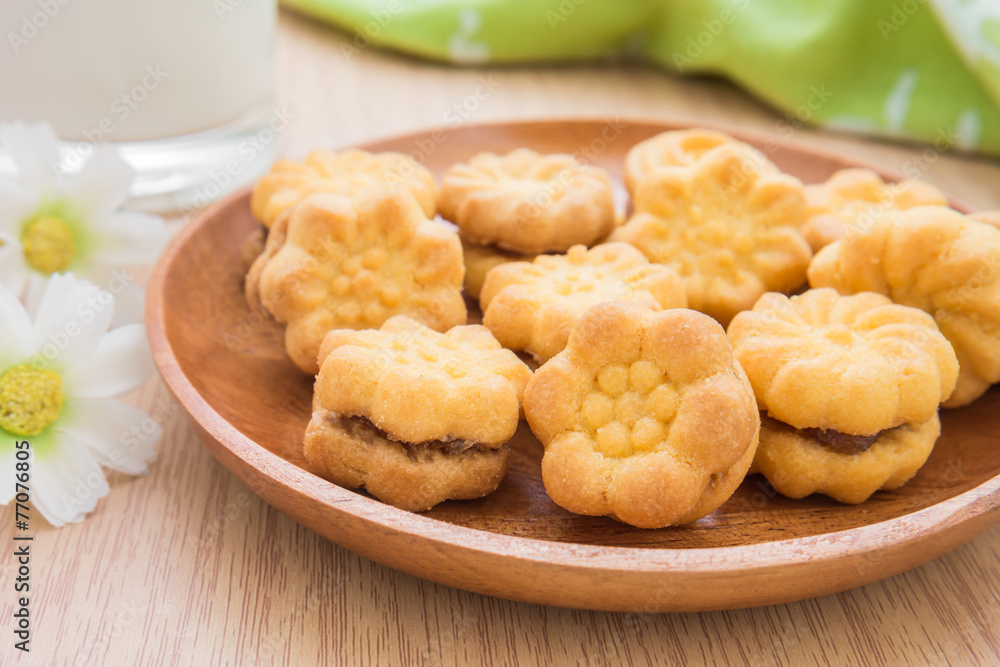 Flower shape biscuits with jam filling on wooden plate Flower shape biscuits with jam filling on wooden plate