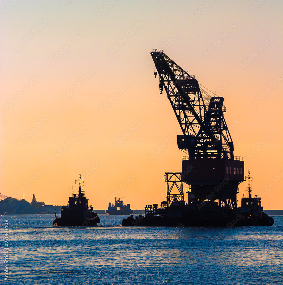 Skyline with silhouette of marine crane platform and barge.