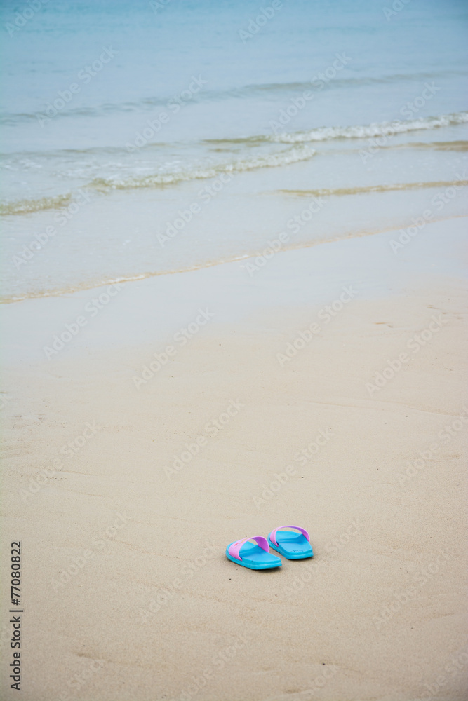 Beach sandals or tongs on a sandy beach
