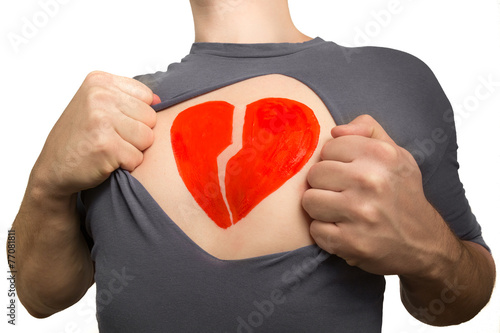 Man tearing apart grey t-shirt. Broken red heart painted on his