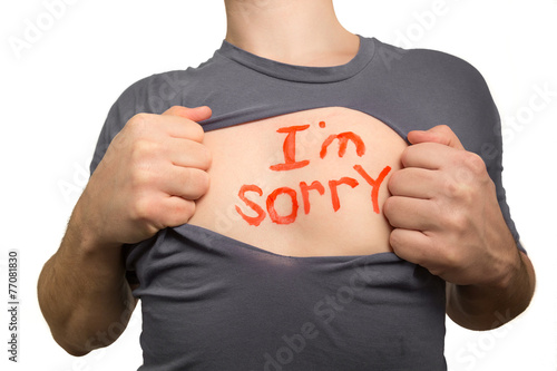 Man tearing apart grey t-shirt. Red text I am sorry written on h