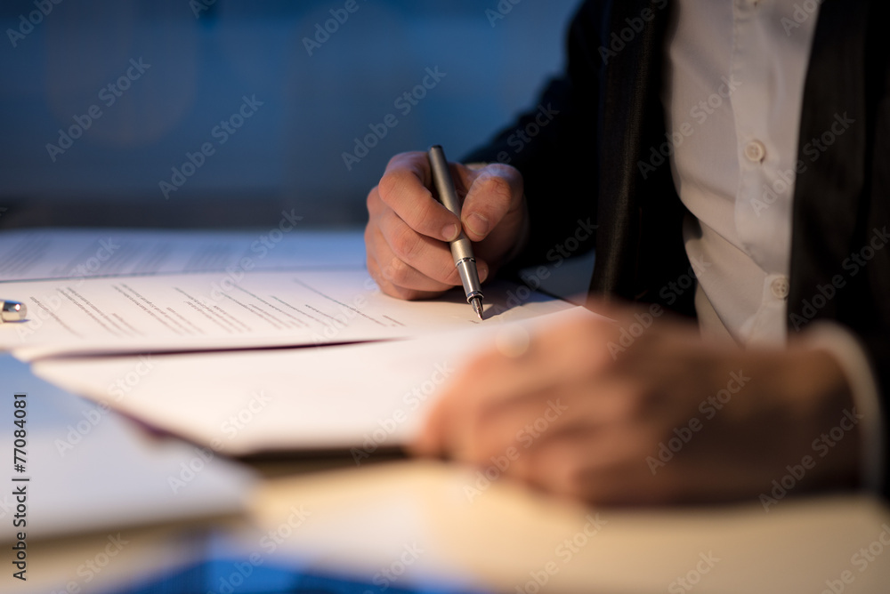 Businessman working late signing a document or contract Businessman working late signing a document or contract