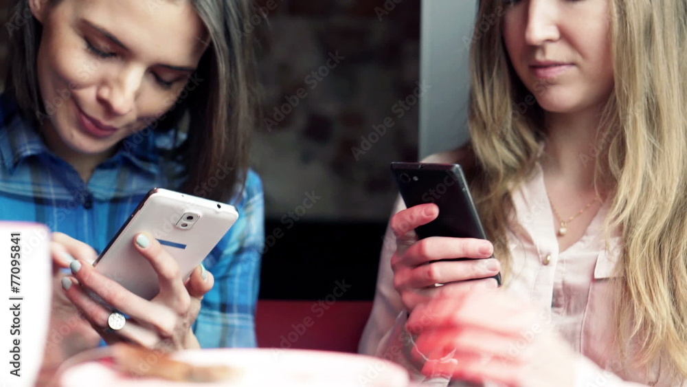 Girlfriends with smartphone sitting in cafe Girlfriends with smartphone sitting in cafe