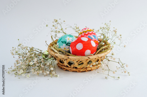 Easter eggs in a basket with hay on a white background