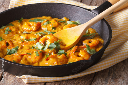 Prawns in curry sauce in a frying pan close-up. Horizontal