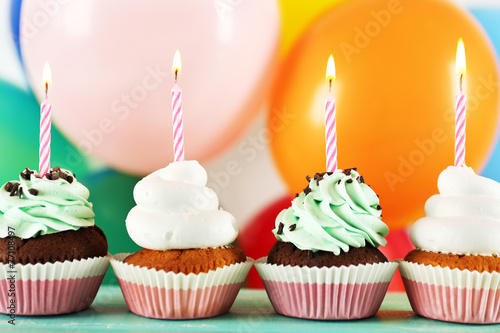 Delicious birthday cupcakes on table on bright background