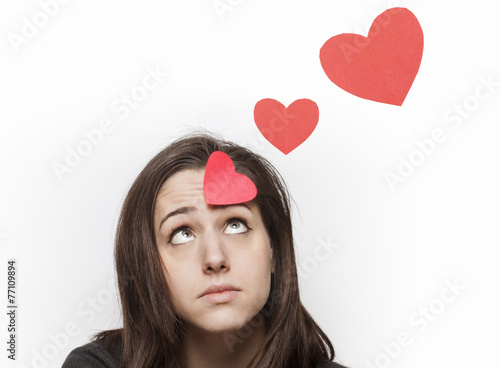 Canvas Print Sad girl looking at red paper hearts