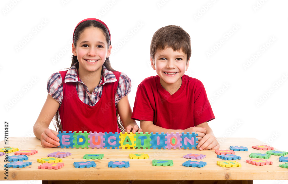 Fototapeta premium Two kids at the table with puzzle letters