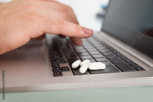 Person Using Laptop With Pills Over Keypad