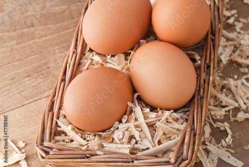 Egg on sawdust with old basket over on wooden background