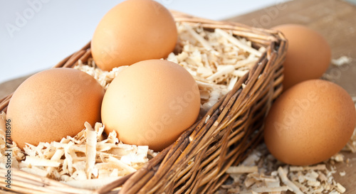 Egg on sawdust with old basket is over on wooden background