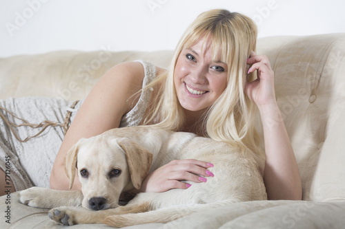 Woman sitting on the white sofa with labrador puppy