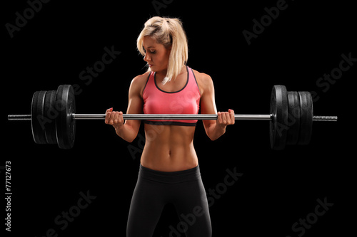 Attractive female athlete exercising with barbell