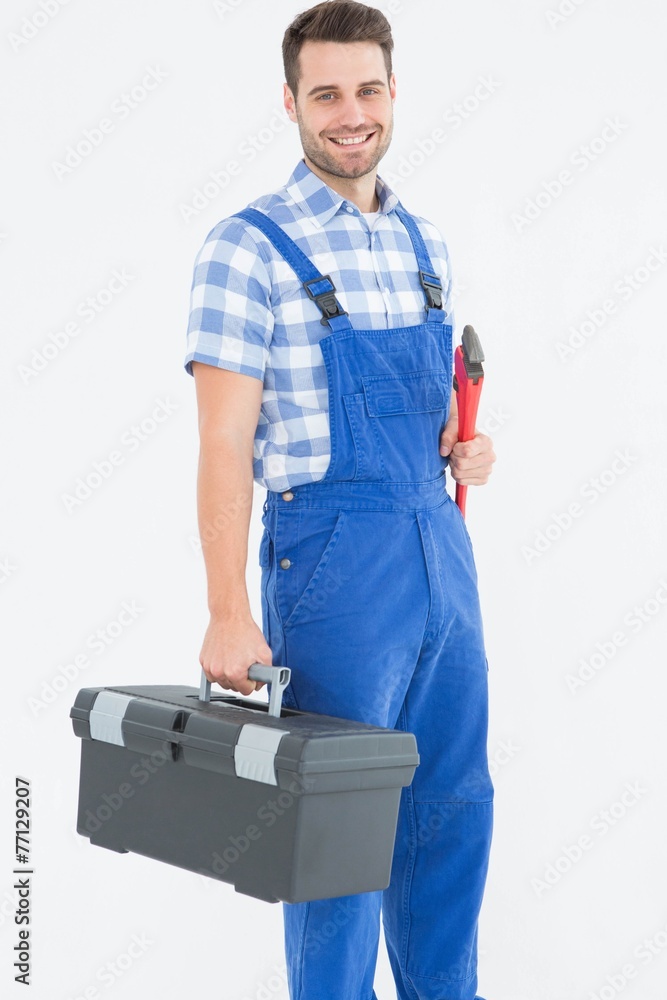 Smiling young male repairman carrying toolbox Smiling young male repairman carrying toolbox