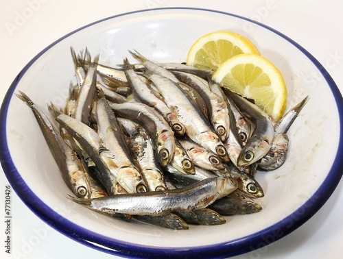 dish with freshly caught raw anchovies and two slices of lemon photo