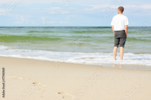 beach man standing water back view shallow dof footprints sand © izuboky