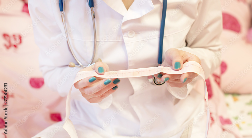 A doctor with a stethoscope checks a patient's cardiogram A doctor with a stethoscope checks a patient's cardiogram