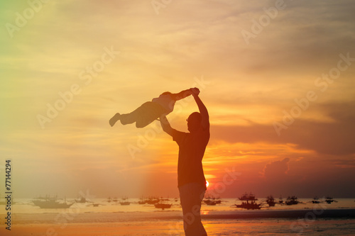 father and son silhouettes play at sunset
