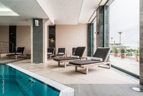 deckchairs near indoors swimming pool © poplasen
