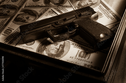 Gun on dollar bills in briefcase. photo