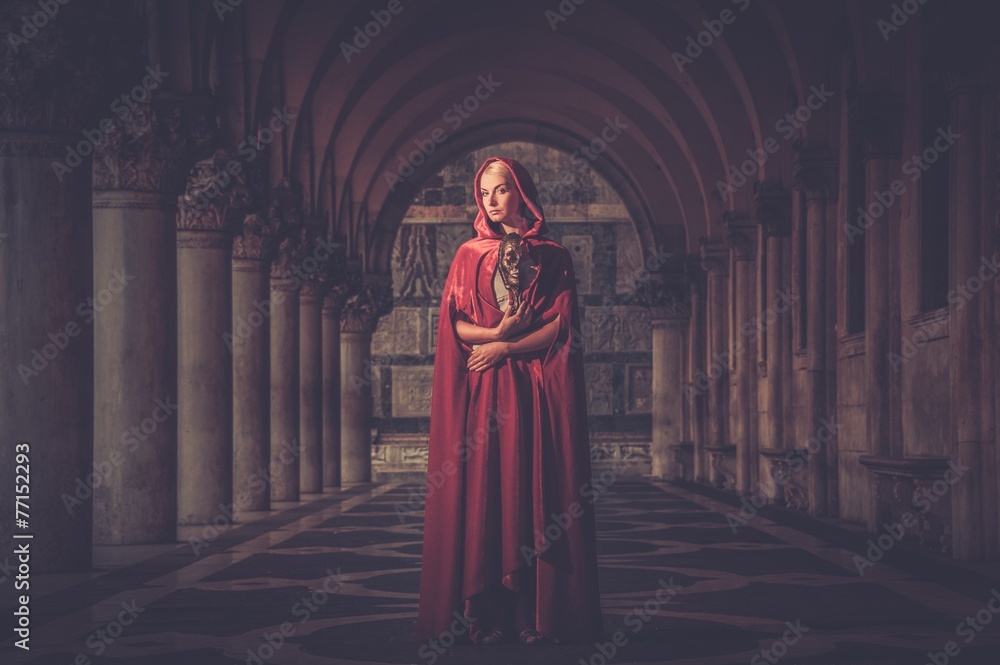 Naklejka premium Woman with a mask wearing red cloak outdoor