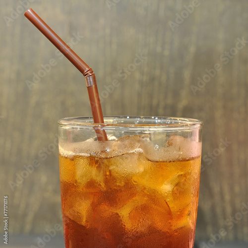 Thai ice tea in glass with brown straw.