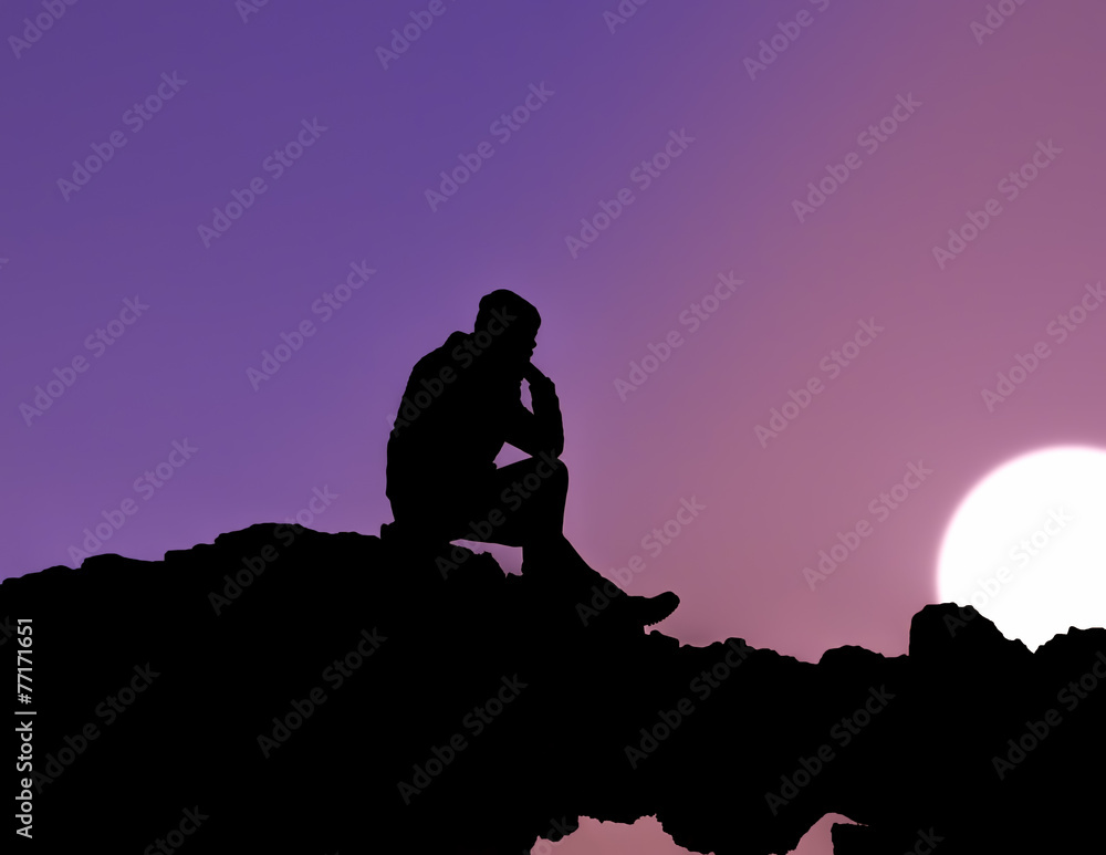 Silhouette of man sitting at sunset
