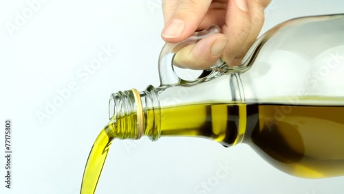 Pouring extra virgin olive oil from glass bottle.  Close up.