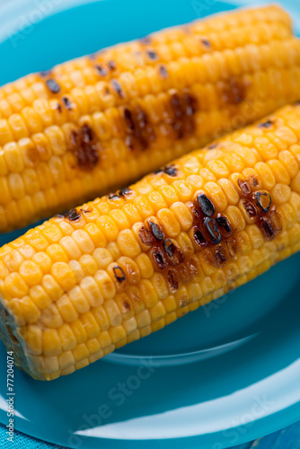 Close-up of grilled corn cobs on a plate, vertical shot