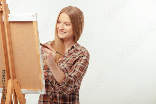 Young beautiful artist posing with a drawing easel