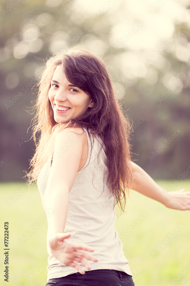 Naklejka premium Beautiful young happy girl with long dark hair in the garden