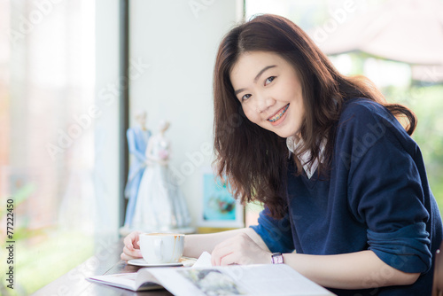 Asian student woman relaxing with hot coffee and Magazine at caf