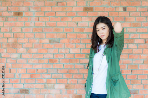 Young asian woman wear green coat stand in front of brick wall b