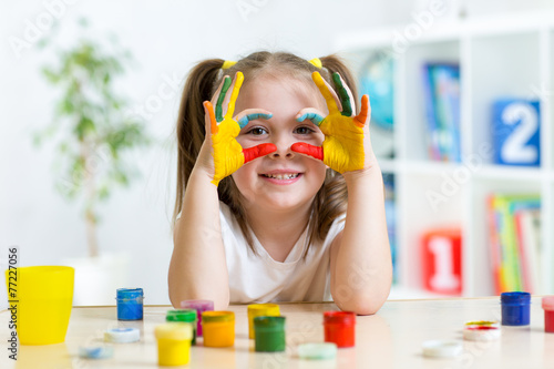 cute kid girl showing her hands painted in bright colors