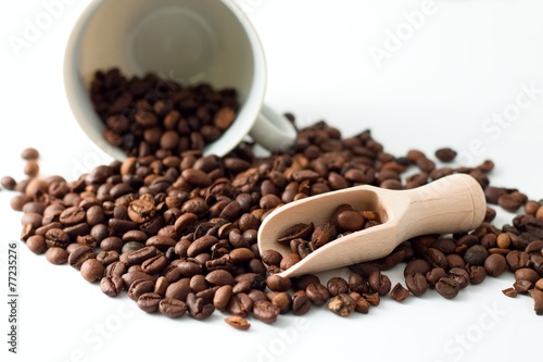 Heap of coffee grains on white board and spilled cup