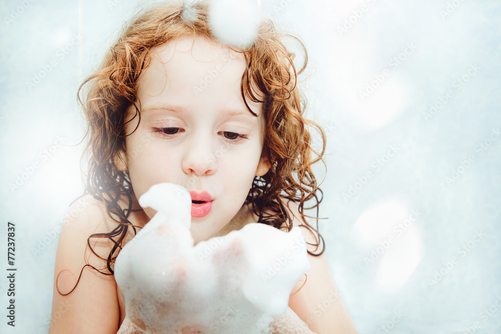 Happy little girl blowing foam with her hand. - obrazy, fototapety, plakaty 