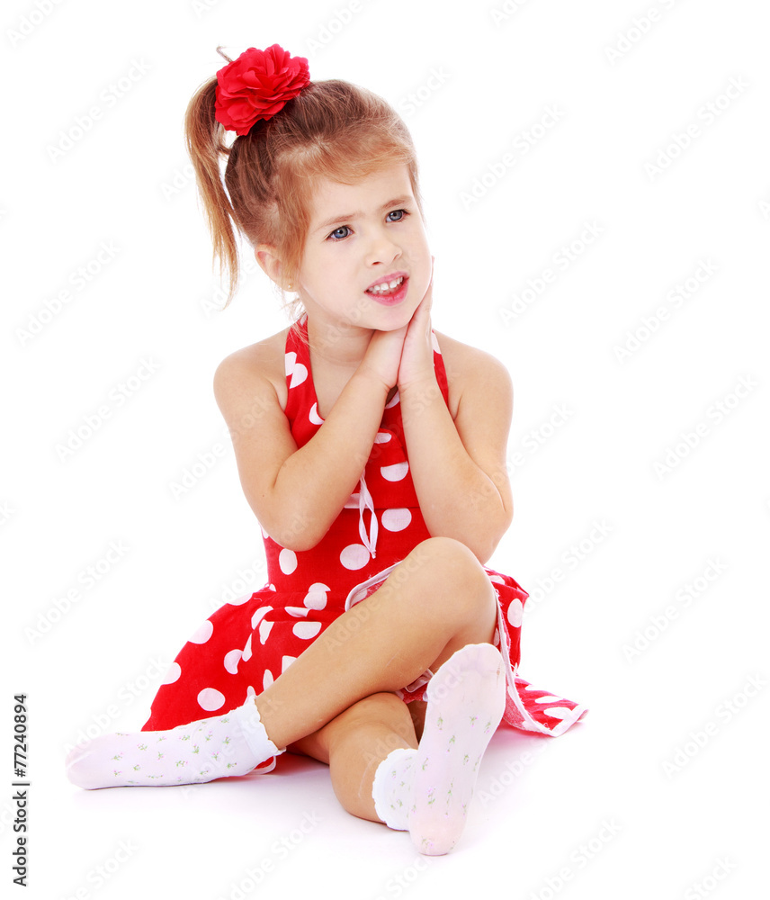 Beautiful little girl sitting on the floor crossed her legs. Stock
