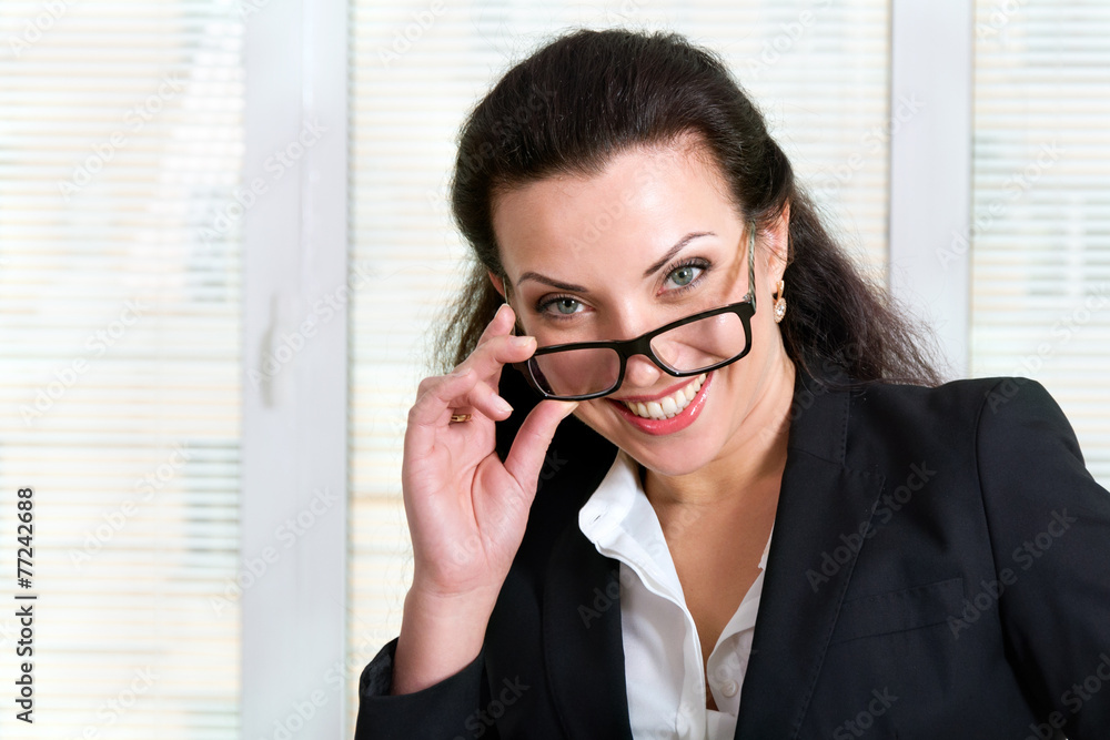 Girl in business attire looking over his glasses and laughs Girl in business attire looking over his glasses and laughs
