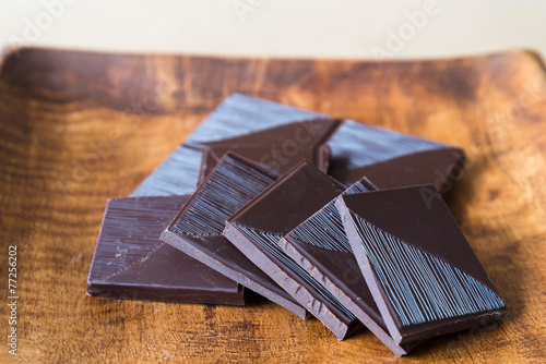 Fotografie horizontal view of broken chocolate bar on wooden plate.