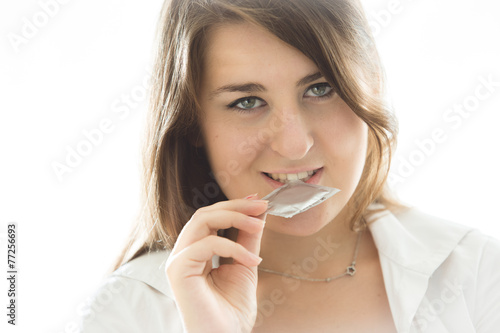 portrait of sexy brunette woman holding condom at mouth
