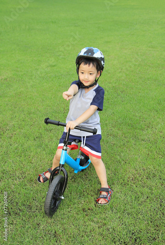 Asian boy riding his bicycle on green field
