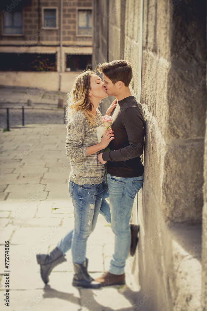 candid portrait couple with rose in love kissing on street alley