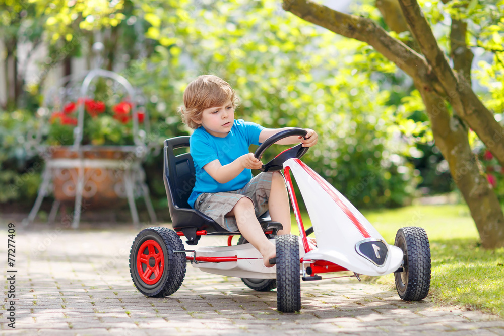 Active little boy having fun and driving toy race car Active little boy having fun and driving toy race car