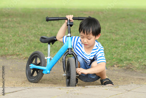 Asian boy with his bicycle in green grass field